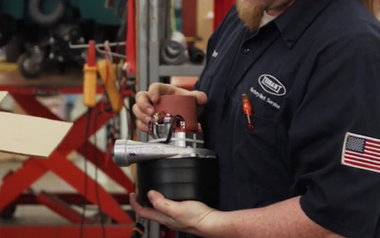 Uma trabalhadora efetua a manutenção de um pavimento de betão polido com uma auto lavadora.